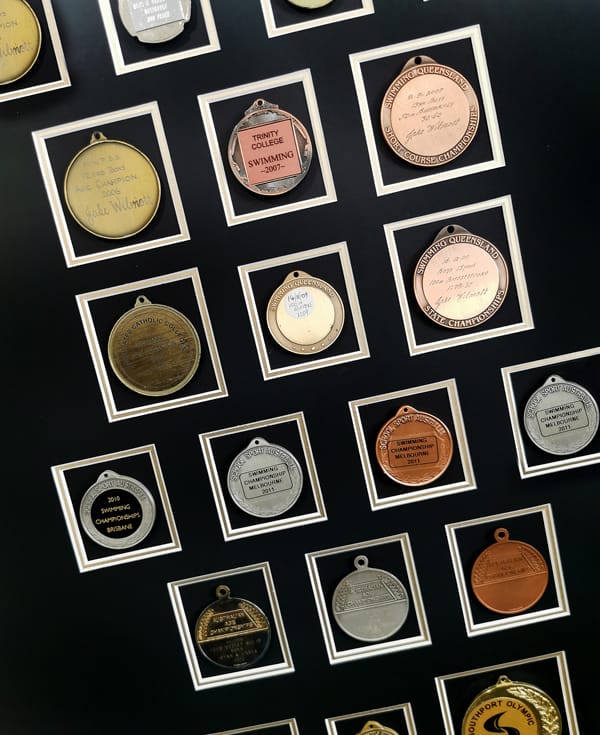 Multiple Swimming medals framed with a double matboard: Memorabilia Items in Complex Arrangements