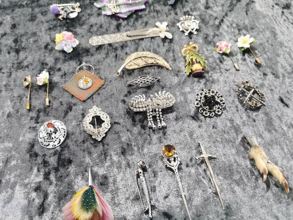 CLOSE UP: An eclectic collection of multiple brooches framed on a velvet backing in a complex arrangement.